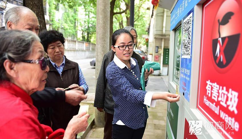 工作人员向居民介绍智能垃圾收集箱的使用方法